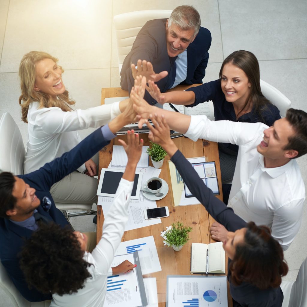 High angle shot of a group of businesspeople high fiving together in an office