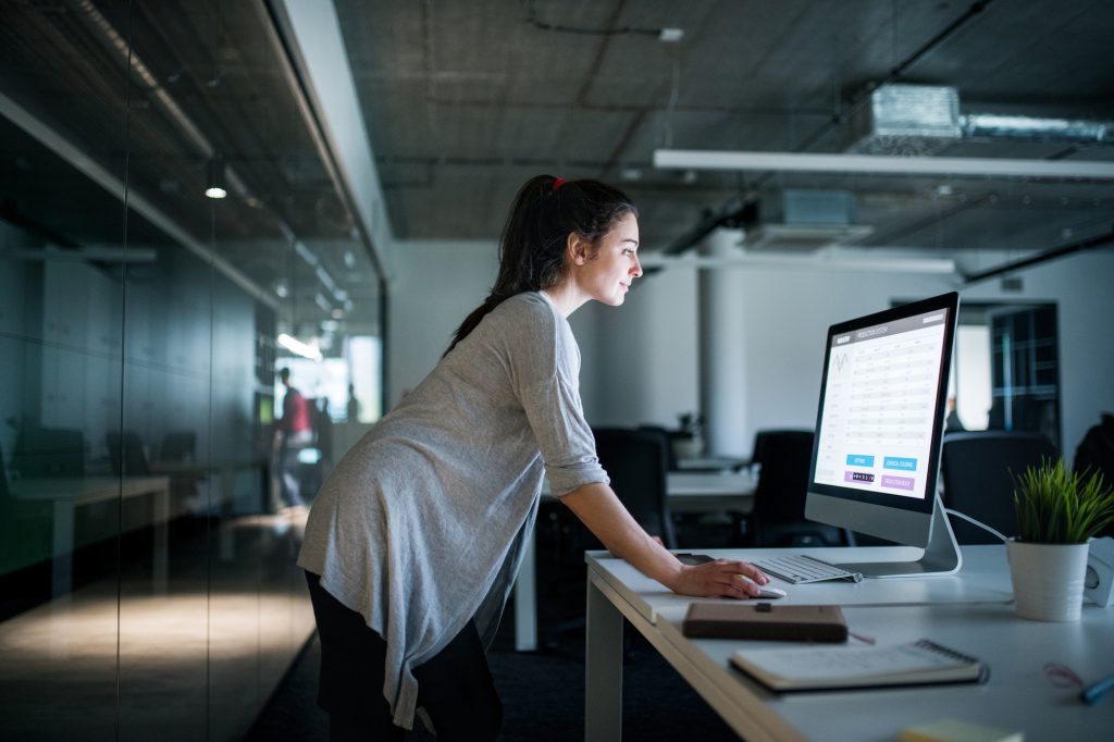 Young businesswoman with computer standing in an office, working